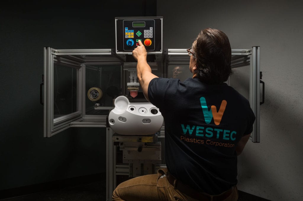 Pad printing over injection molded parts and Westec Plastics Corp machine operator using a large hot pad printing machine
